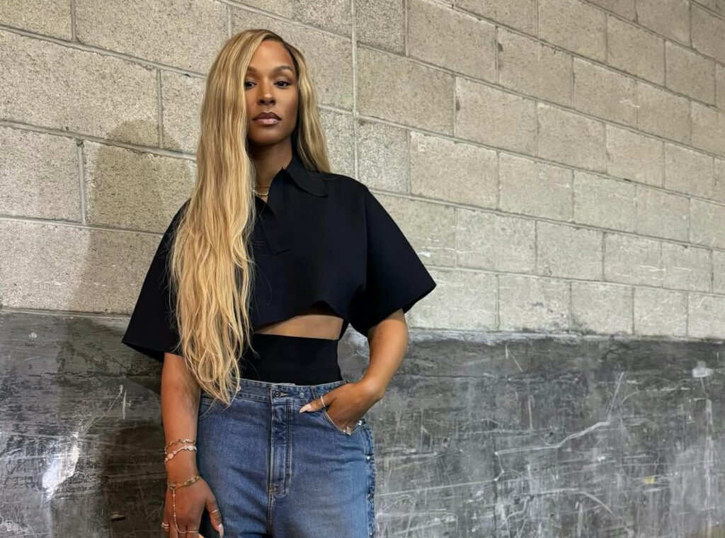 Savannah James Attends Basketball Game Wearing an Alaia Cropped Black Polo Shirt, Snap Denim Jeans, Louis Vuitton Green Speedy, and Bottega Veneta Mules